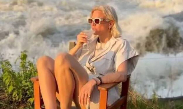 Η Χριστίνα Κοντοβά πίνει το ποτό της με φόντο τους καταρράκτες στην Ουγκάντα