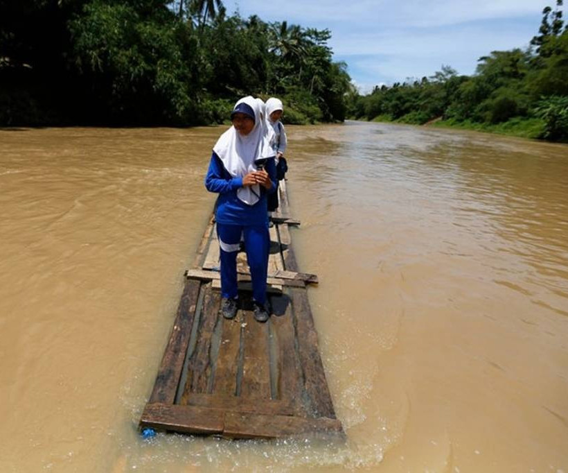 Μαθητές περνάνε ποταμό πάνω σε μια σανίδα. Ινδονησία
