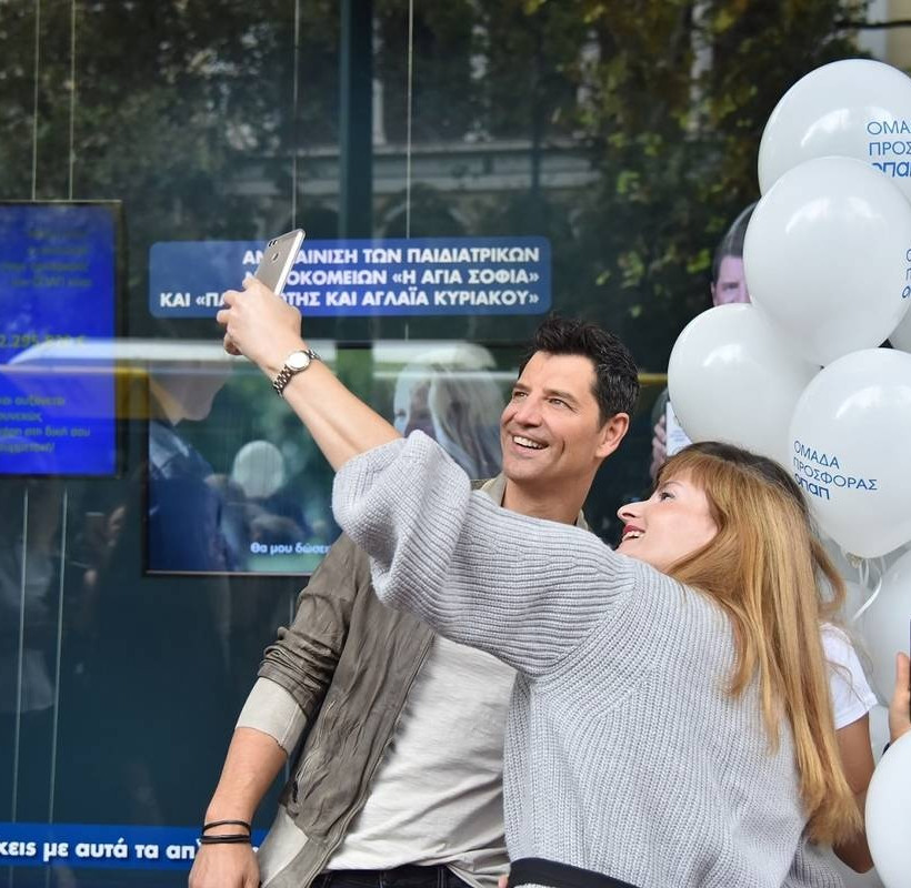 O Σάκης Ρουβάς φωτογραφίζεται με μέλη της ομάδας προσφοράς ΟΠΑΠ