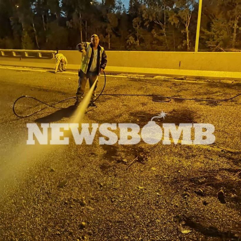 Υπάλληλοι καθαρίζουν με νερό τον δρόμο που κάηκε το αυτοκίνητο 