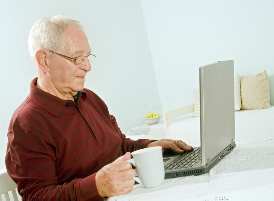 ηλικιωμενος πινει καφε μπροστα σε laptop